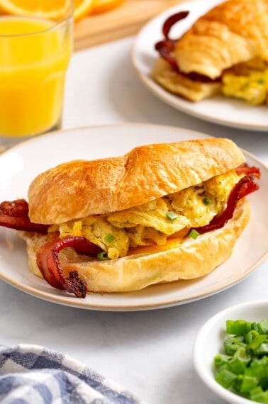 A croissant breakfast sandwich on a plate.