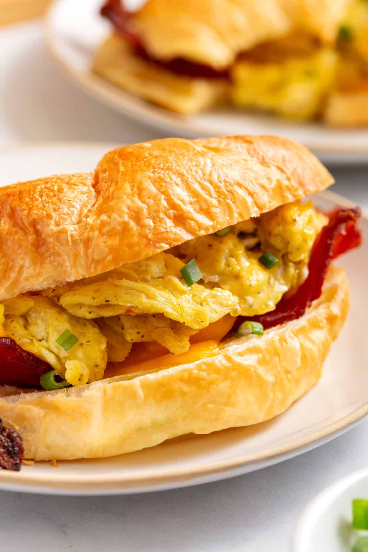 Close-up image of a croissant, breakfast sandwich served on a plate.