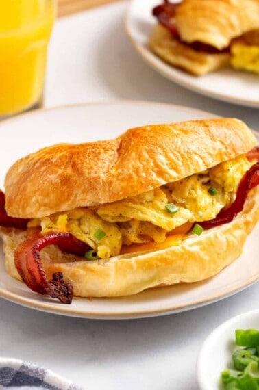 A croissant breakfast sandwich on a plate.