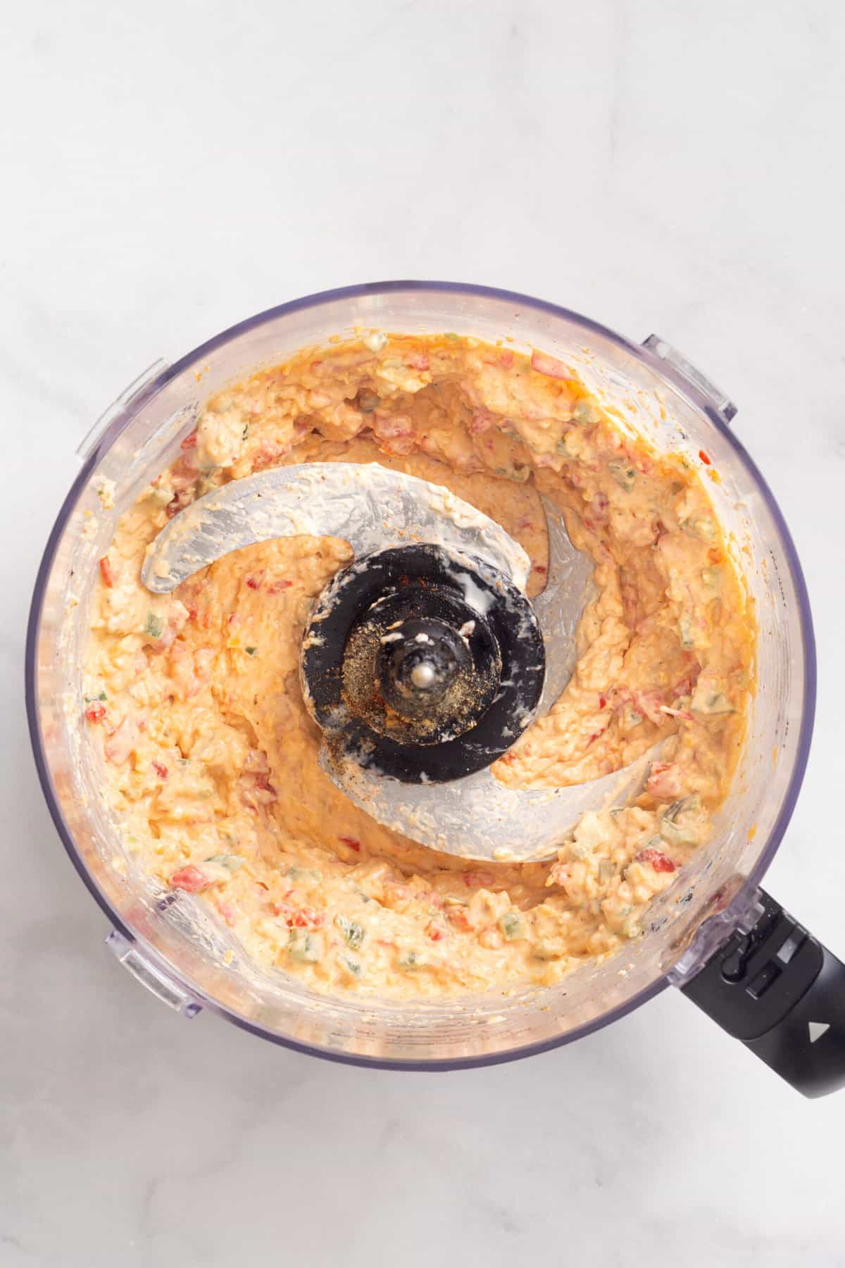 Top an image of a food processor with pimento cheese dip combined.