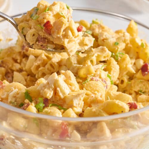 A spoon lifting a scoop of deviled egg pasta salad from a bowl.
