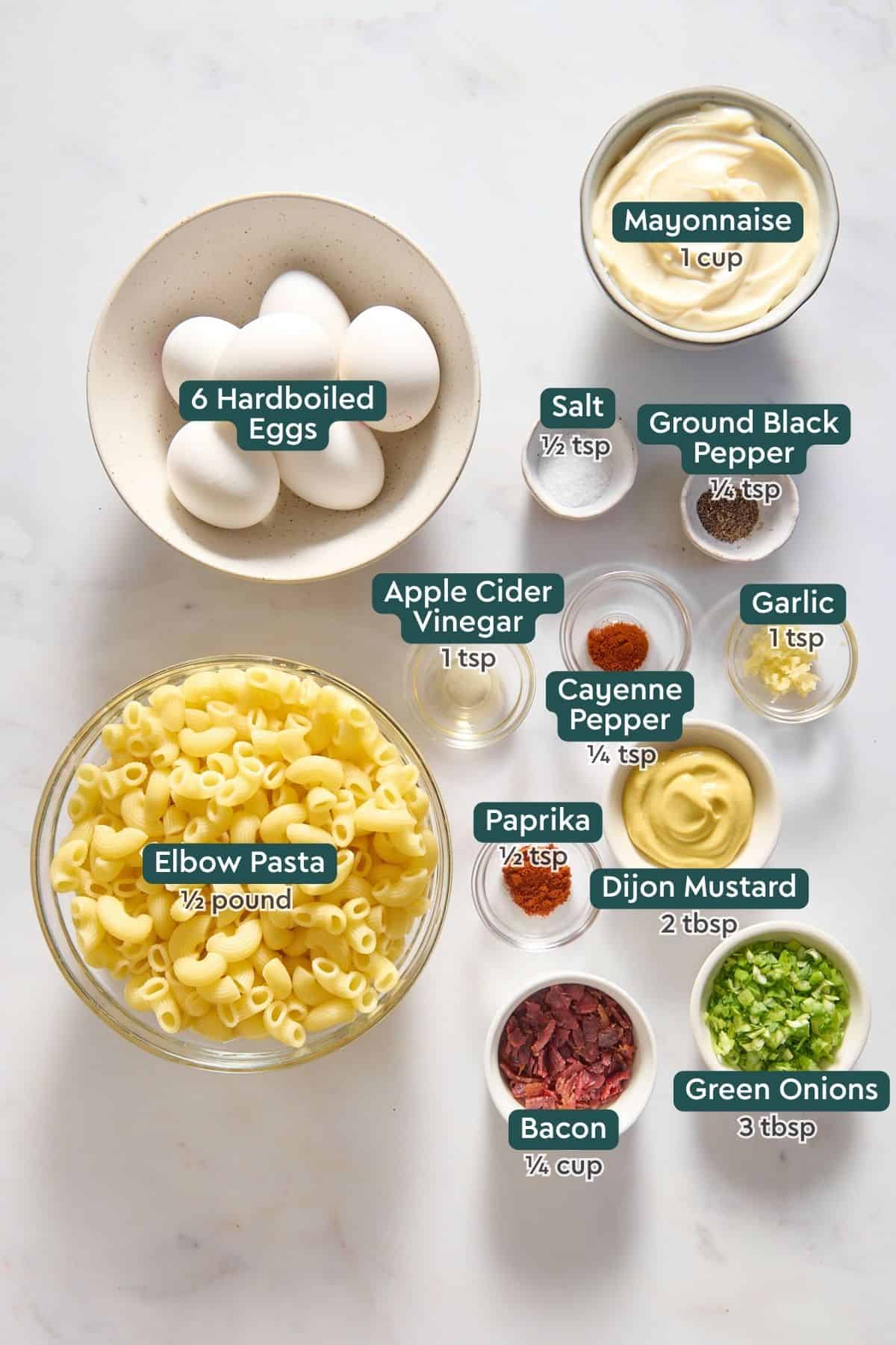 Ingredients for deviled egg pasta salad, including mayo, eggs, spices, garlic, mustard, bacon, pasta, green onions.