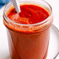 A jar of red enchilada sauce with a spoon sticking out.