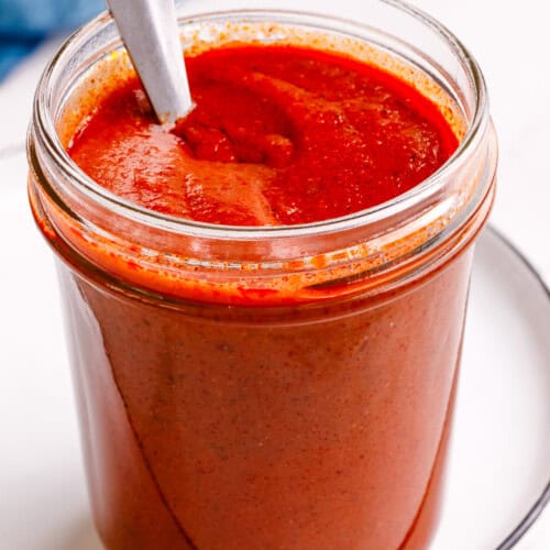 A jar of red enchilada sauce with a spoon sticking out.