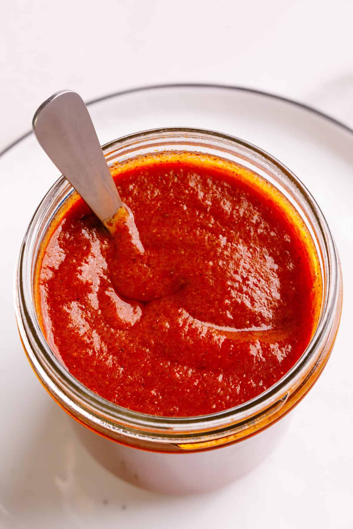 Top down close-up image of red enchilada sauce in a mason jar.