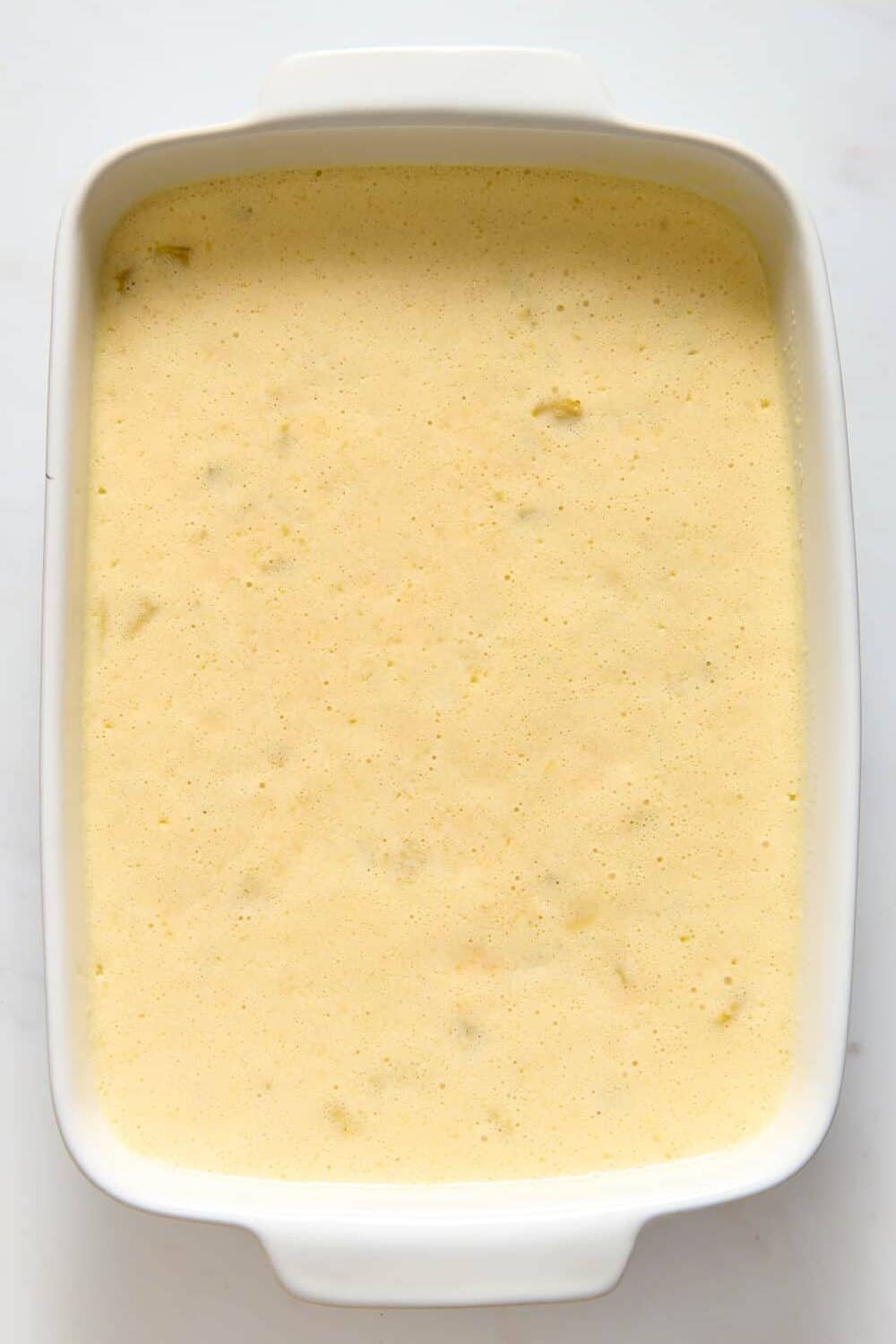 Top 10 image of green chili egg casserole mixture prepared in a 9 x 13" casserole dish.