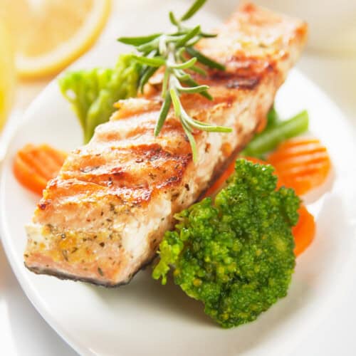 Grilled salmon on a plate over vegetables.
