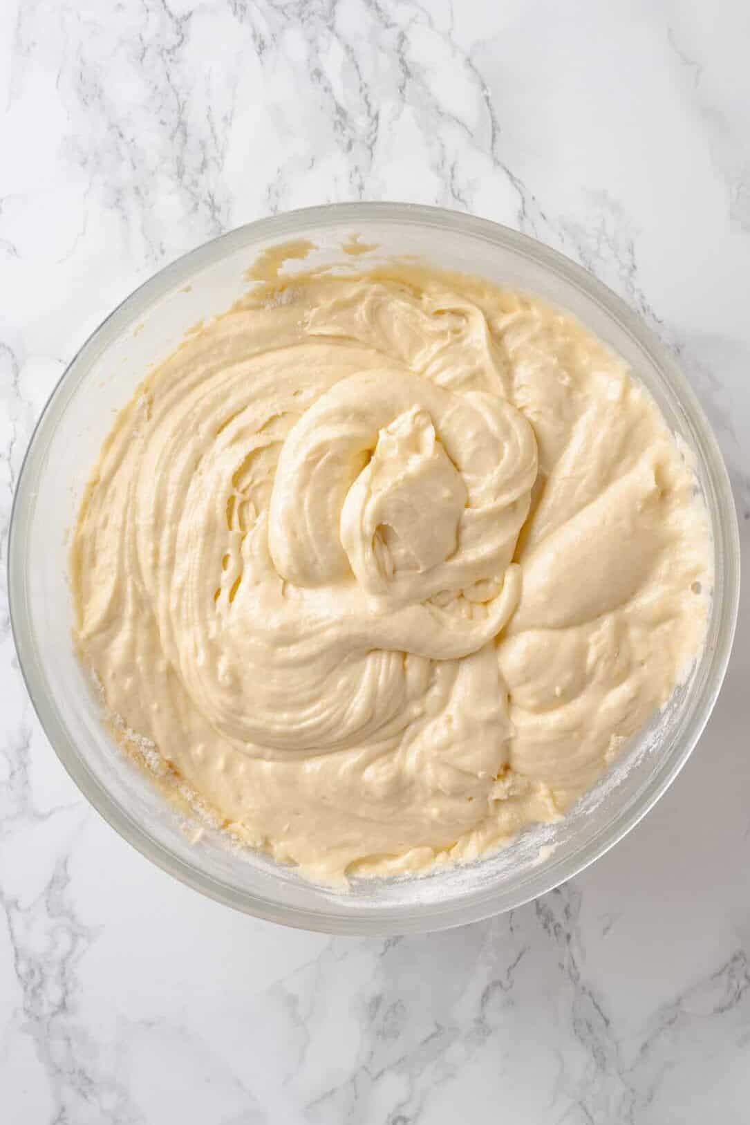 Image of a large glass mixing bowl with lemon pound cake batter.