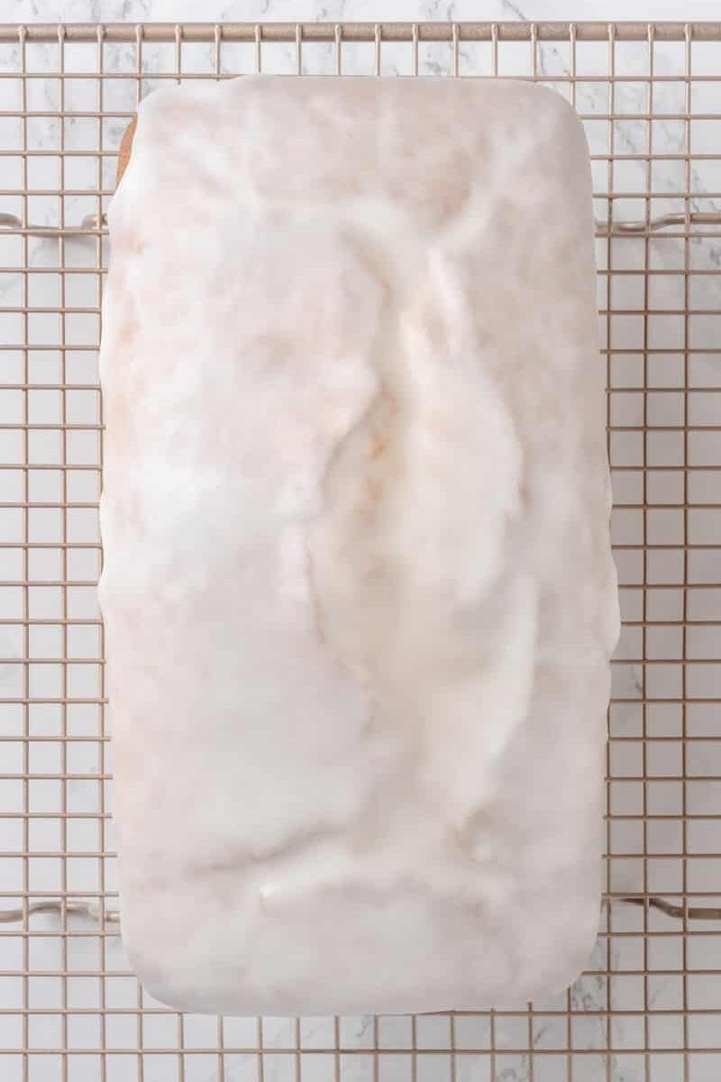 Top gun image of lemon, pound cake, glazed sitting on a cooling wire rack.