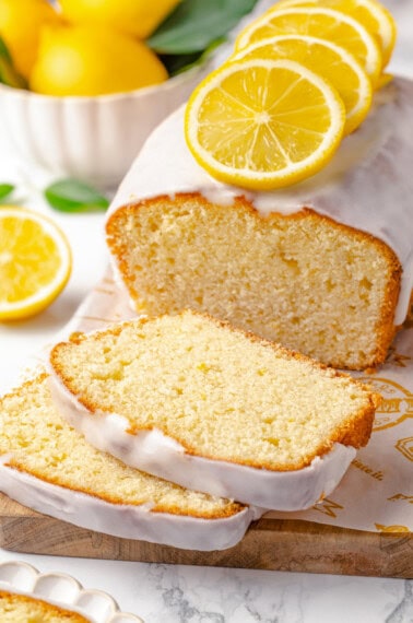 An iced lemon pound cake with two slices cut.