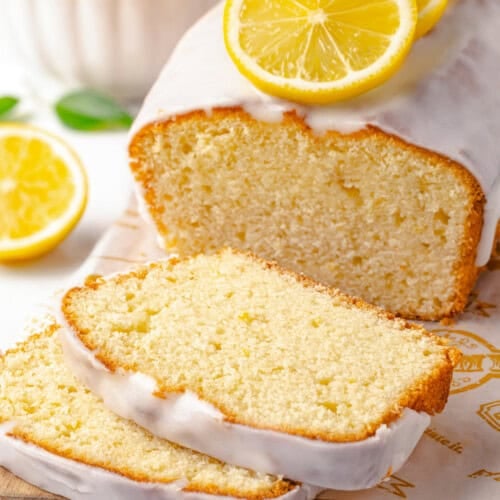An iced lemon pound cake with two slices cut.