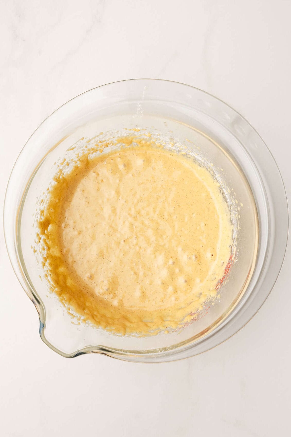 top down image of a large glass mixing bowl with morning glory muffin batter without the fruit and nut mix-ins.