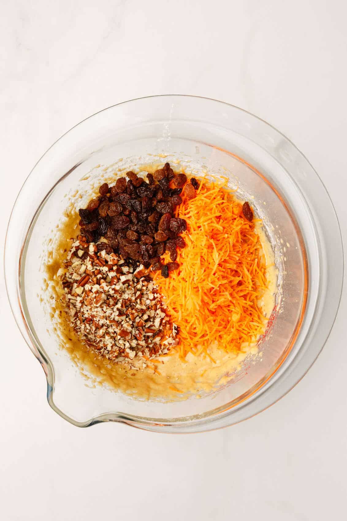 top down image of a large glass mixing bowl with morning glory muffin batter. 