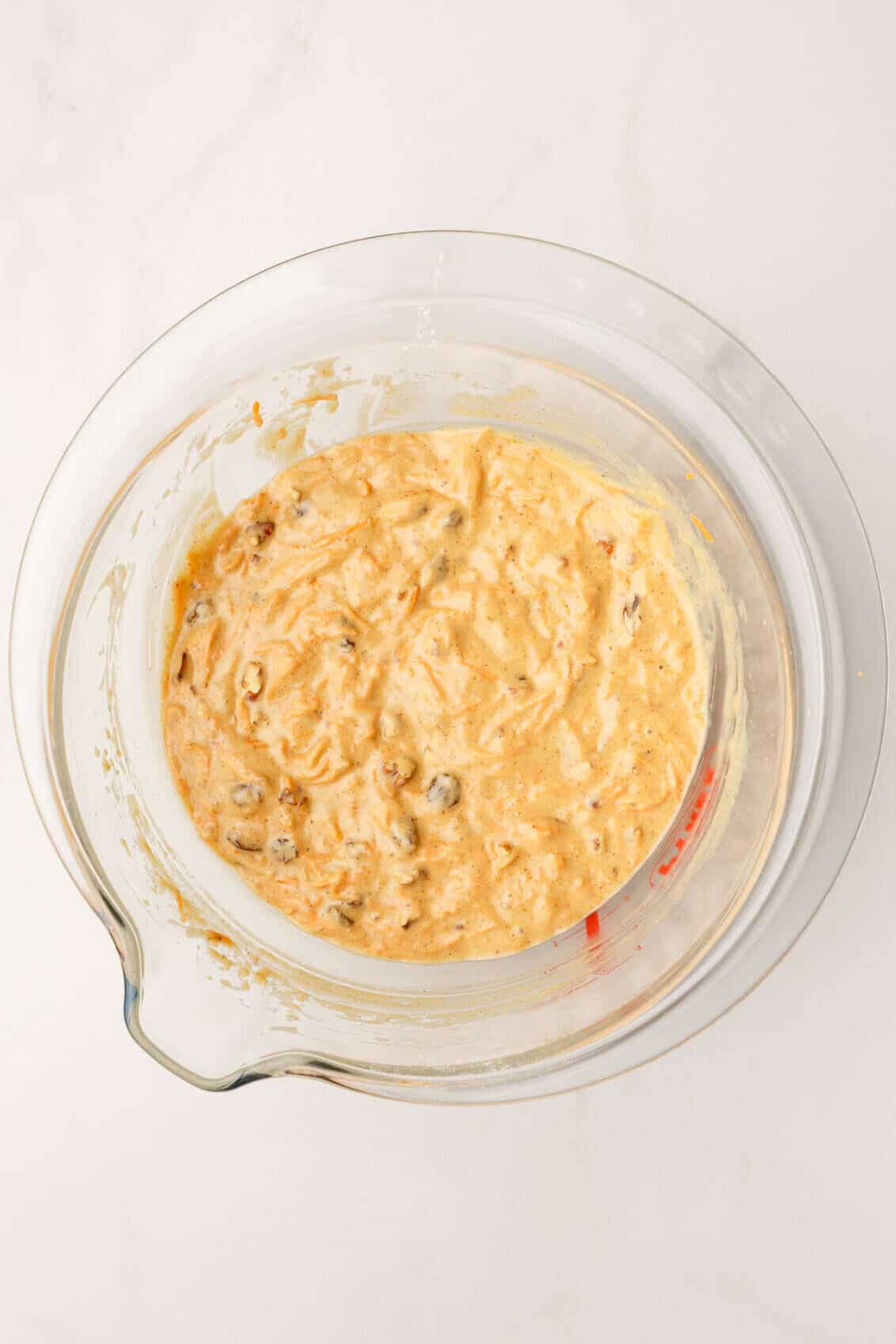 top down image of a large glass mixing bowl with morning glory muffin batter. 