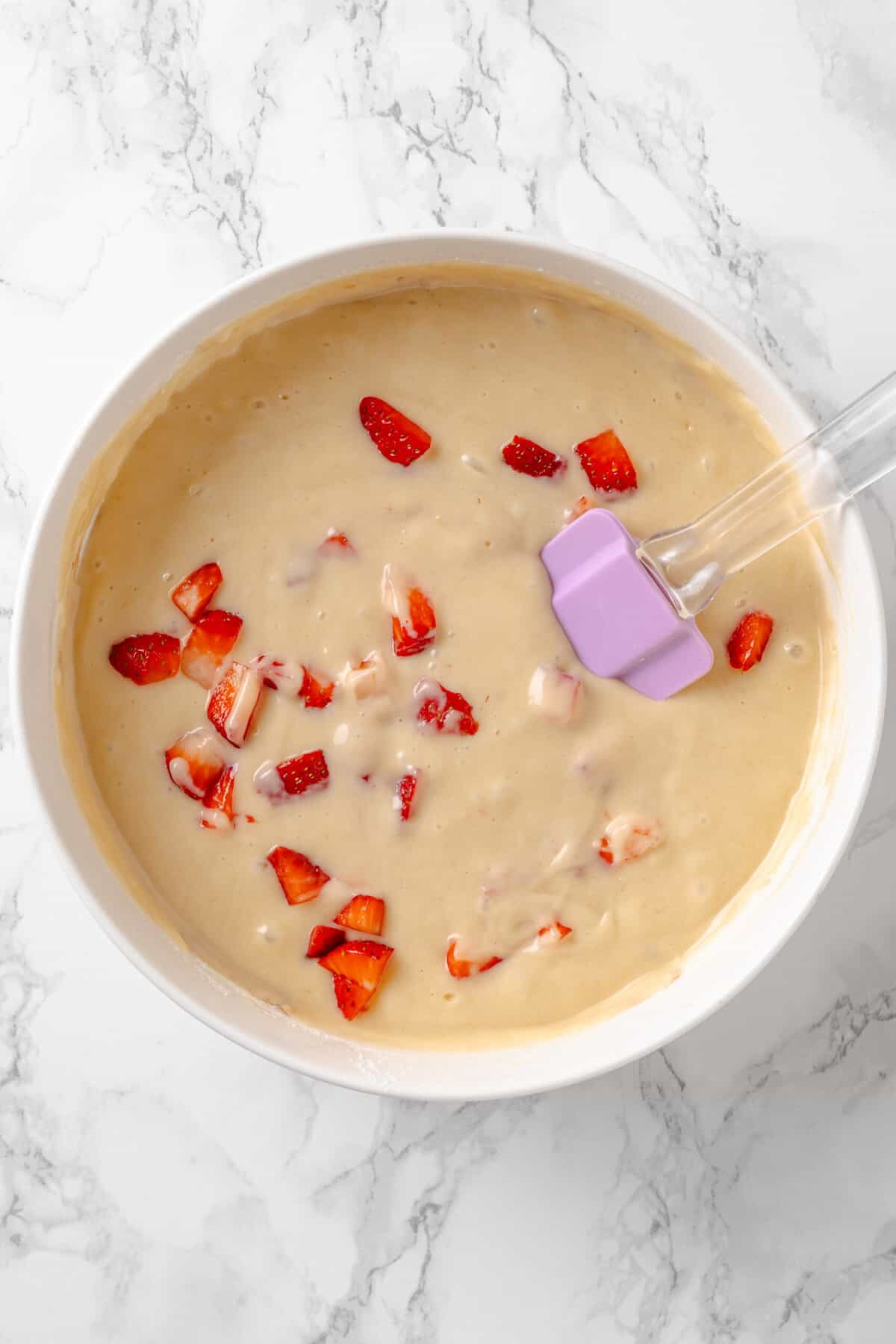Top down image of a white mixing bowl with strawberry pound cake batter.