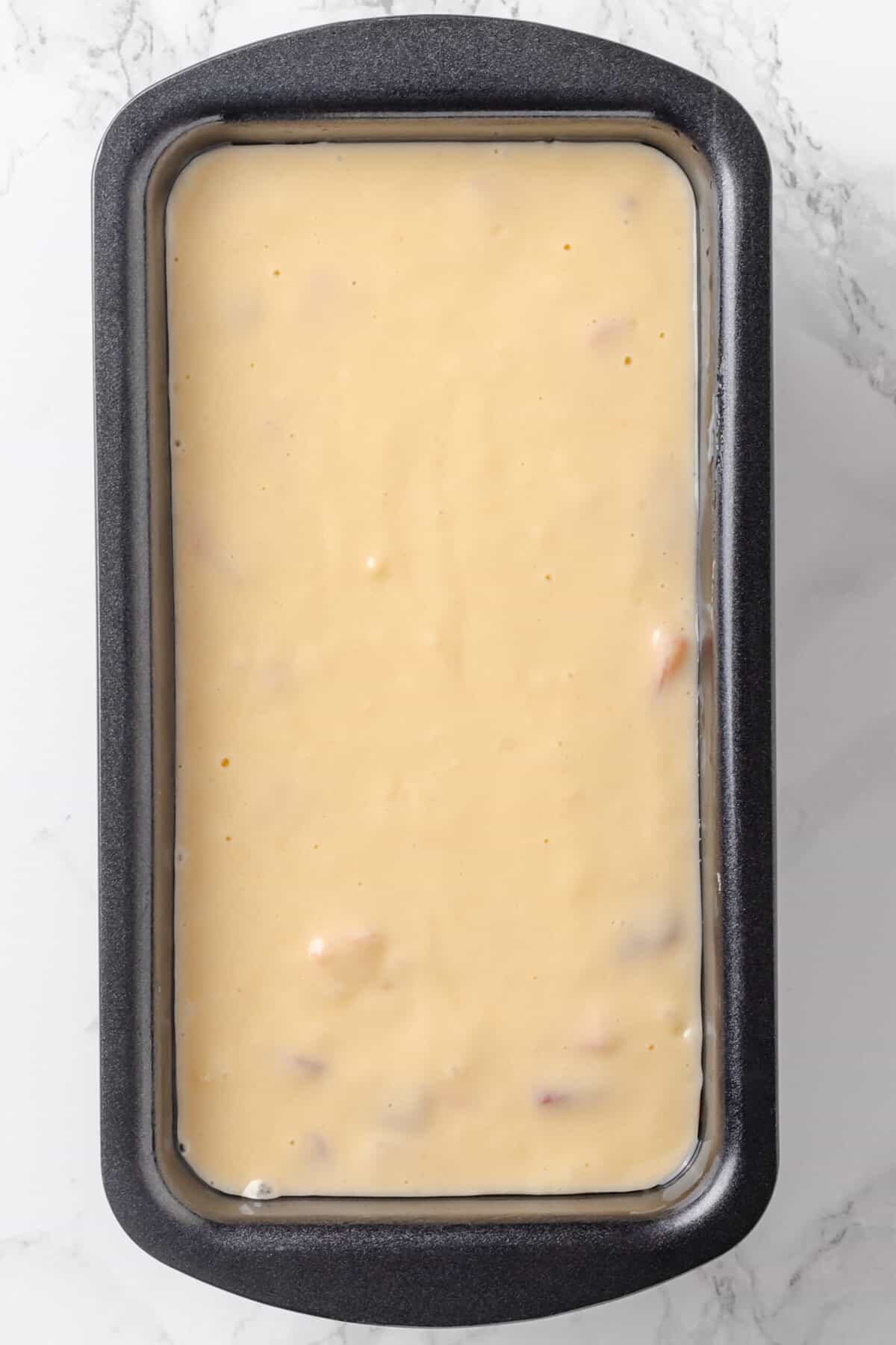 Top down image of a loaf tin with strawberry pound cake batter.