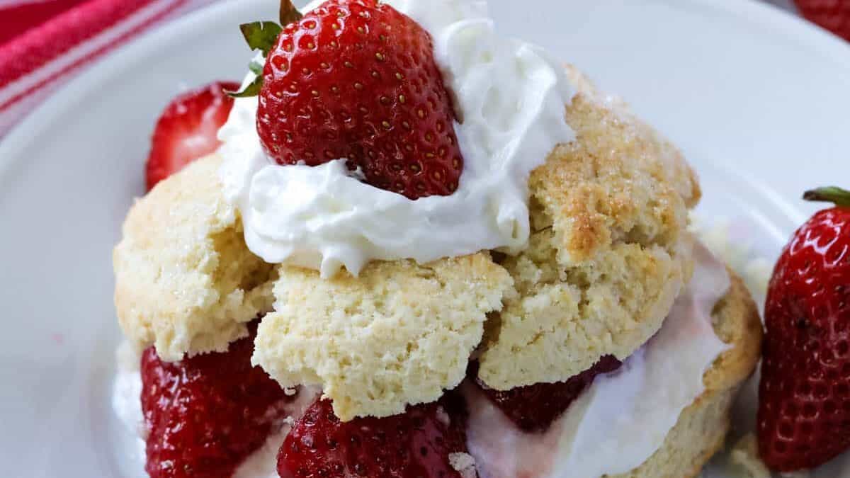 Crumbly strawberry shortcake with strawberries and whipped cream on a white plate
