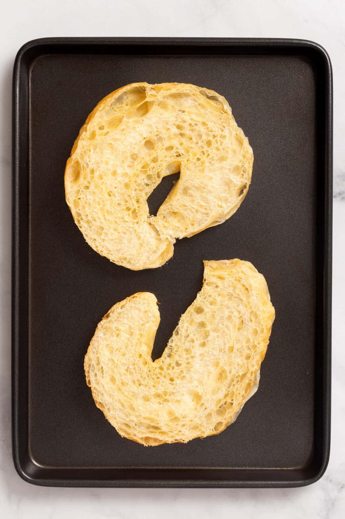 Top down image of a croissant, cut in half and placed on a baking tray.