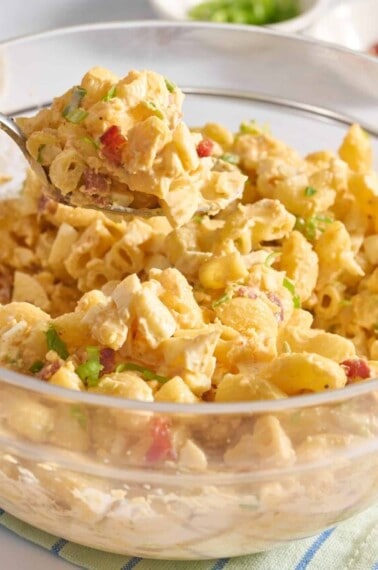A spoon lifting a scoop of deviled egg pasta salad from a bowl.