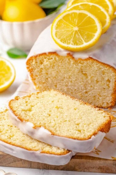 An iced lemon pound cake with two slices cut.