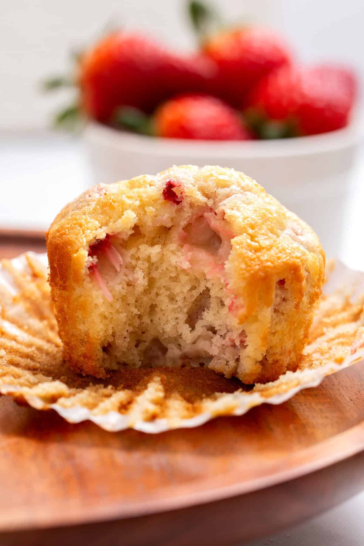 Close-up image of a strawberry muffin with a bite taken out of it.