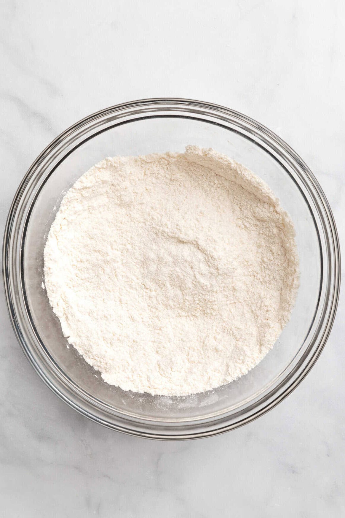 Top down image of a large glass bowl with flour.