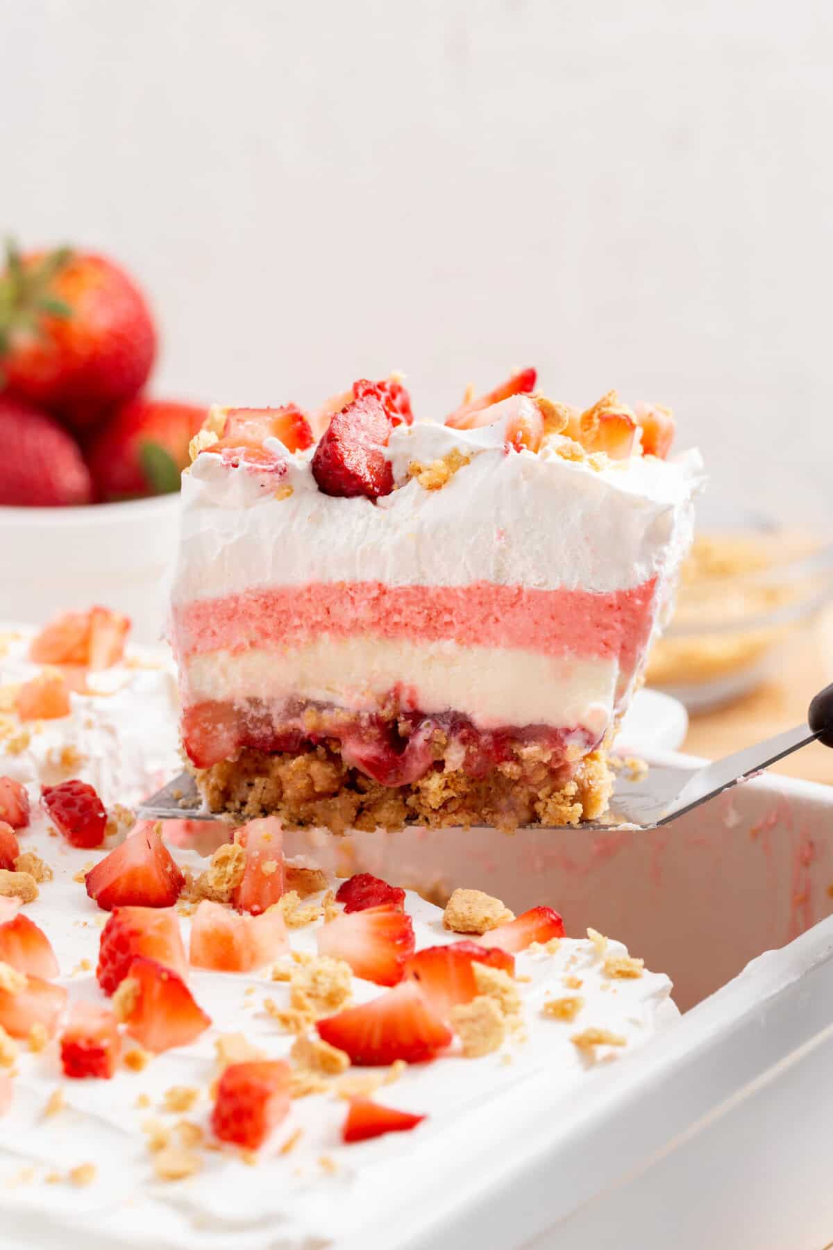 A square slice of strawberry delight sitting on a metal spatula.