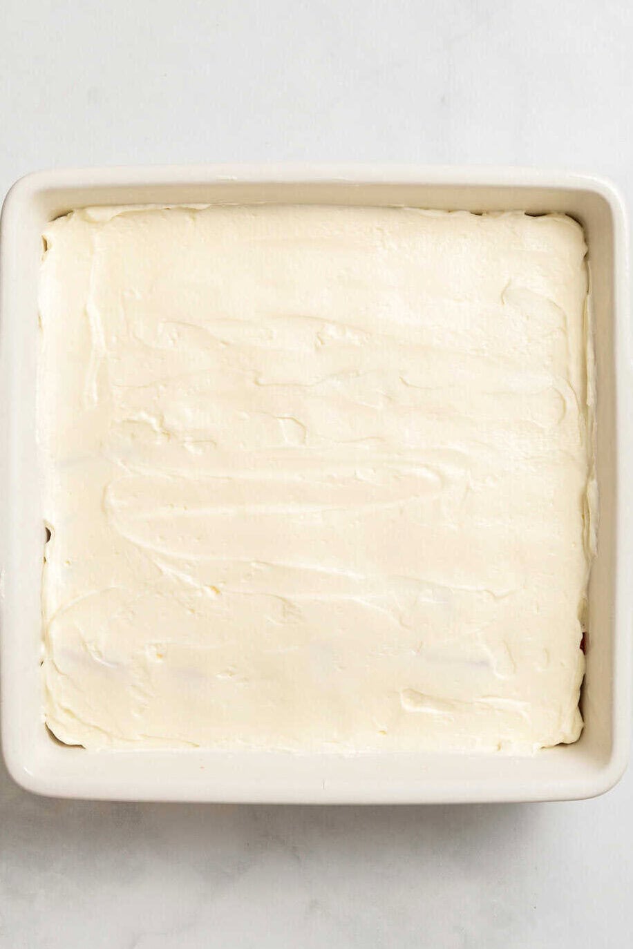 top down image of an 8 x 8 baking dish with cream cheese layer.