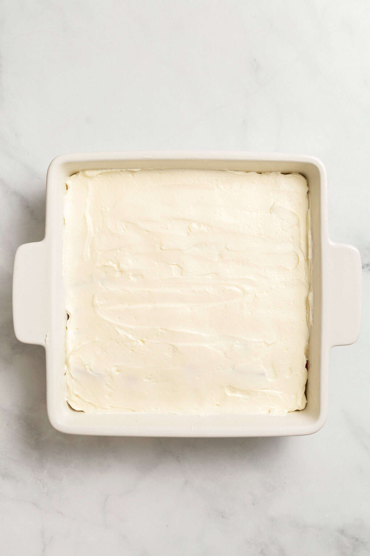 Cream cheese layered in dish for strawberry delight.