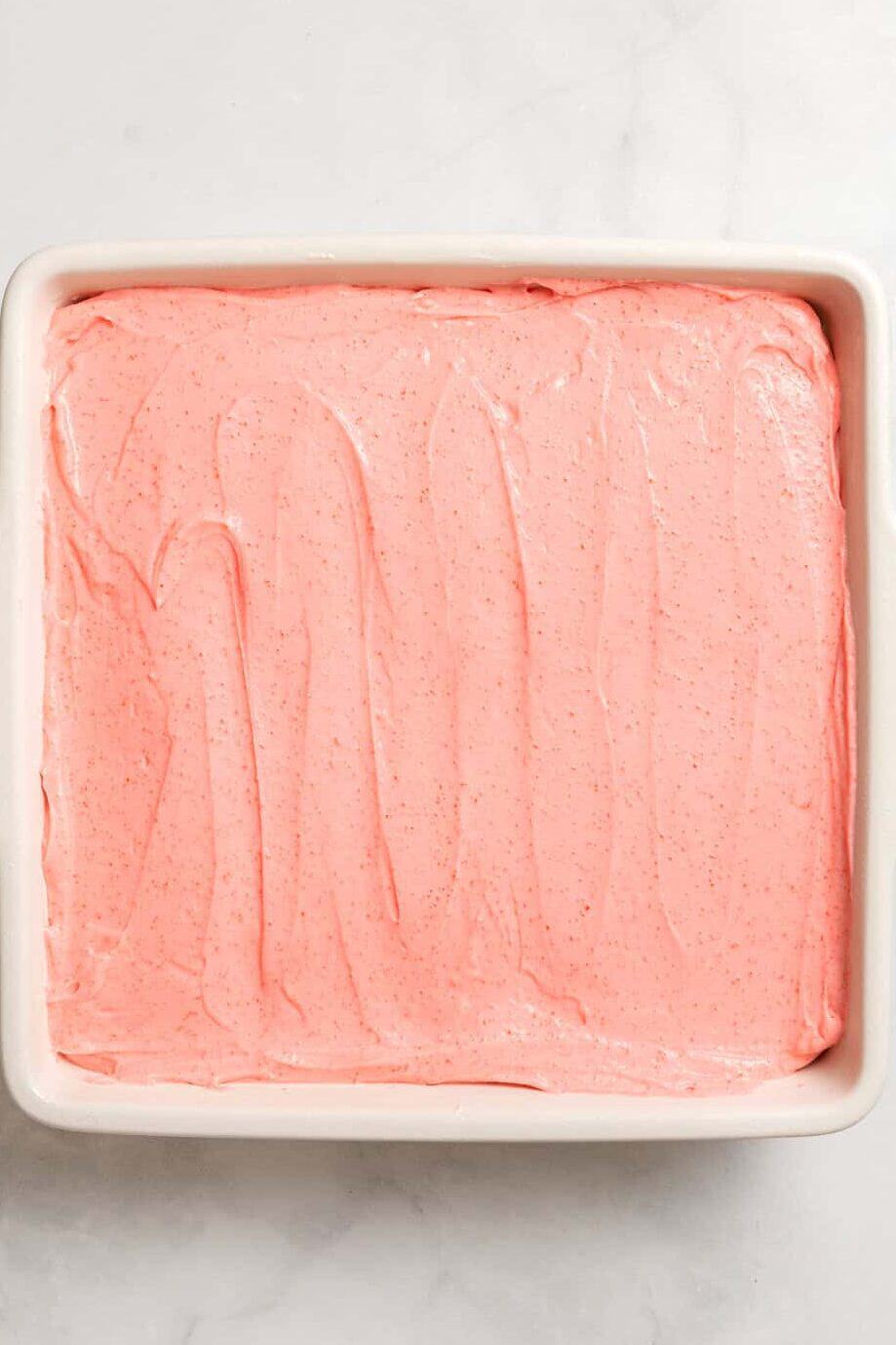 top down image of an 8 x 8 baking dish with a strawberry Jell-O dessert layer.