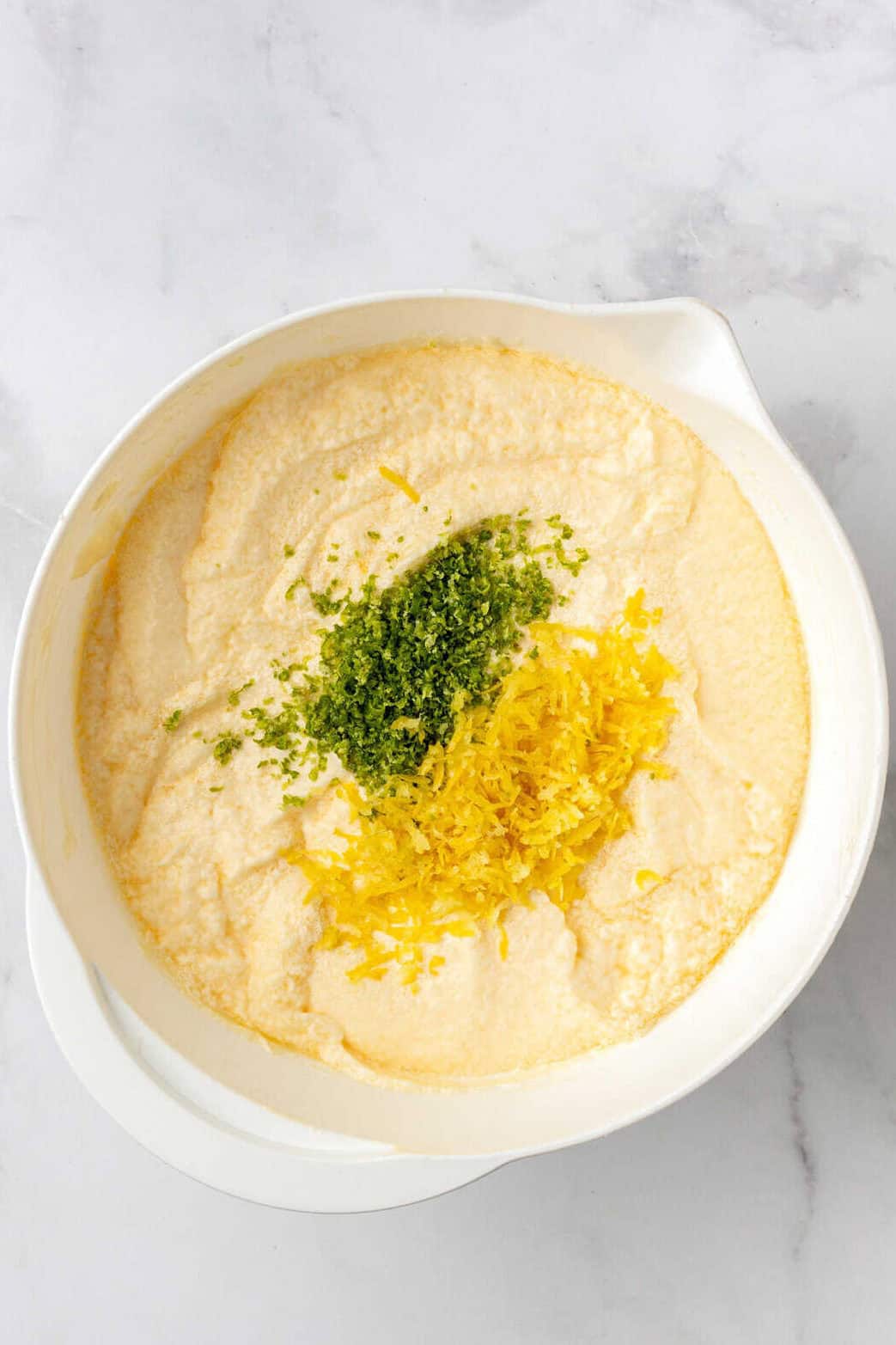 cake batter in a white bowl with lemon zest and lime zest.