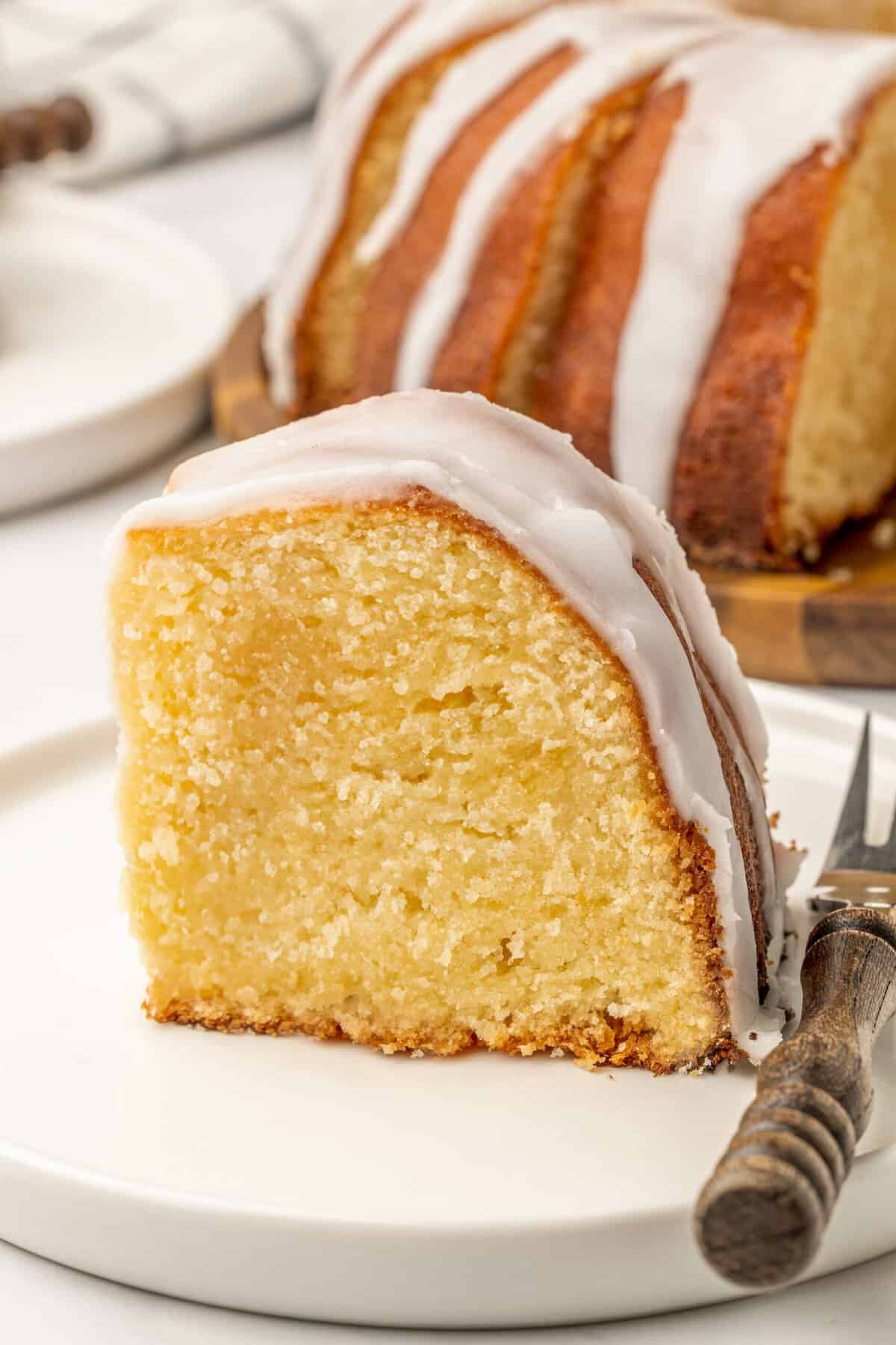 a slice of 7up pound cake with white glaze on a white cake.