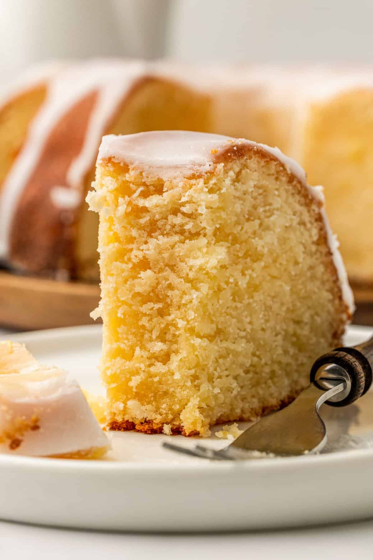 close up image of a slice of 7UP pound cake sitting on a white round plate. 