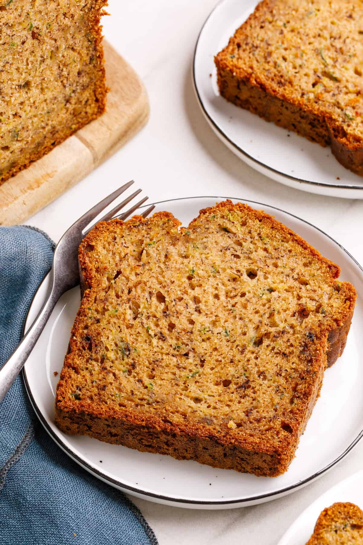 slice of banana zucchini bread on a white plate with a fork.