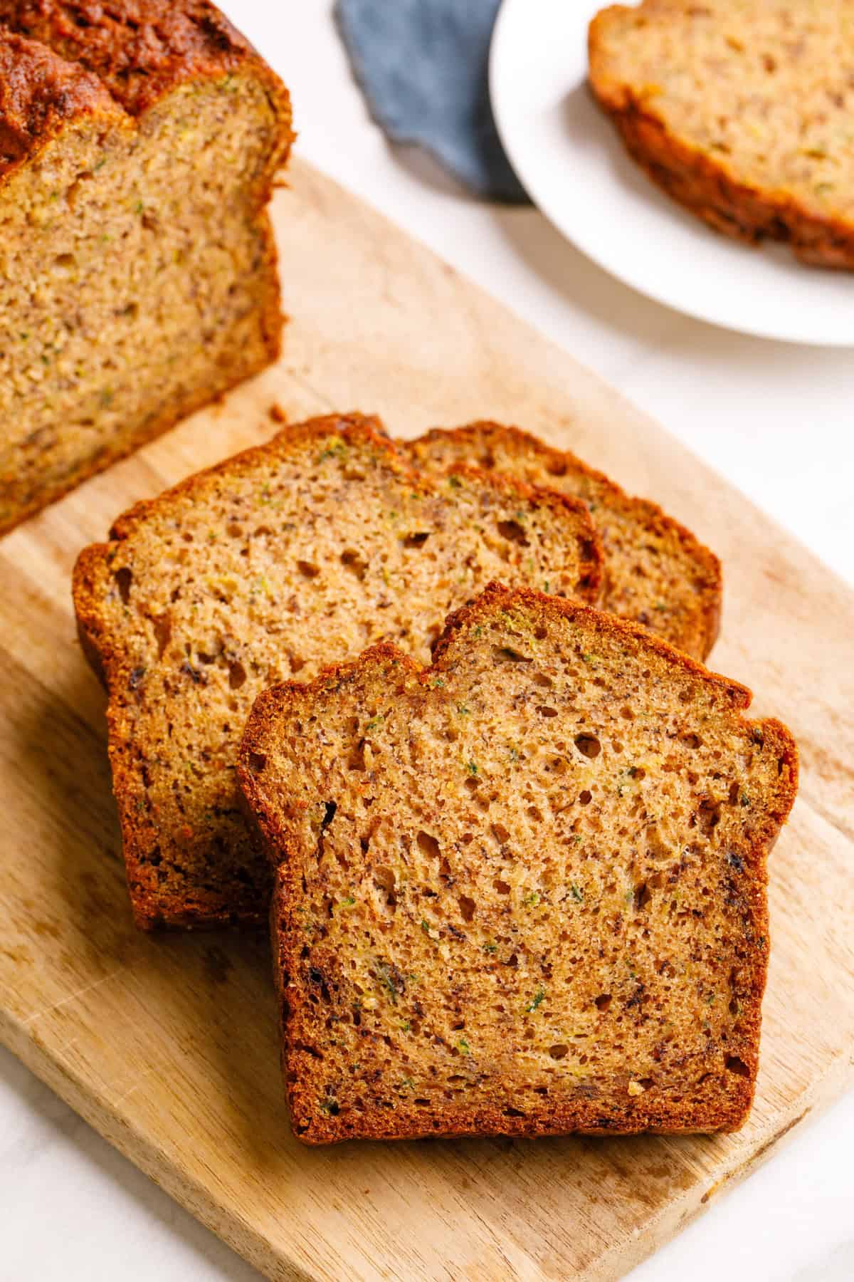 slices of zucchini banana bread on a wooden cutting board. 