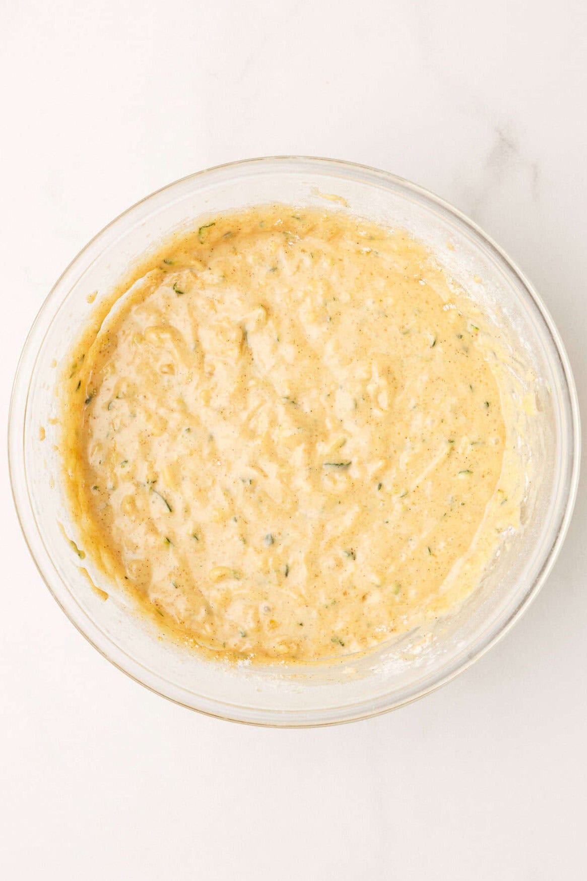 mixing the banana zucchini bread ingredients in a large glass bowl.
