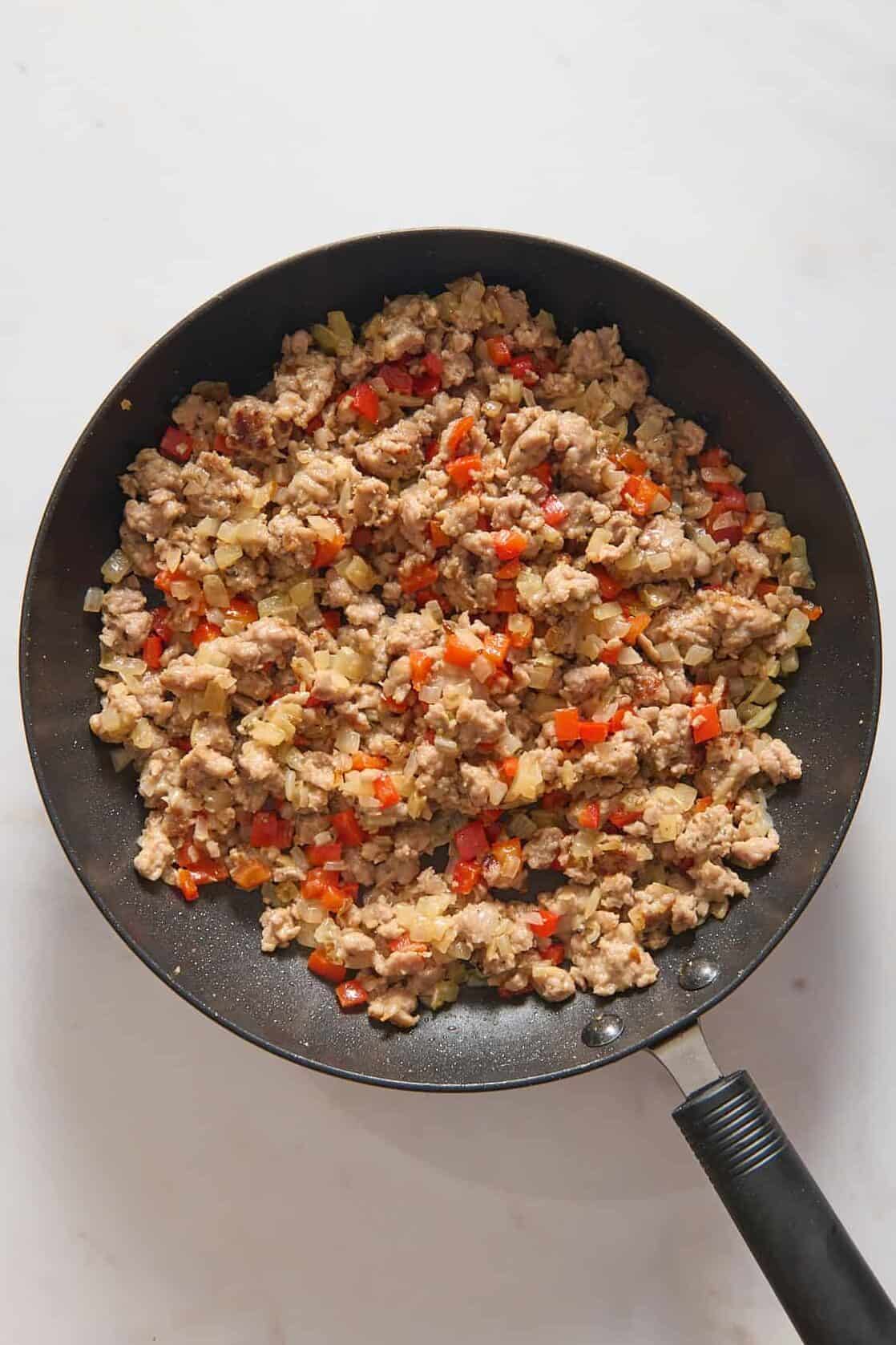 Breakfast sausage and red bell pepper in skillet.