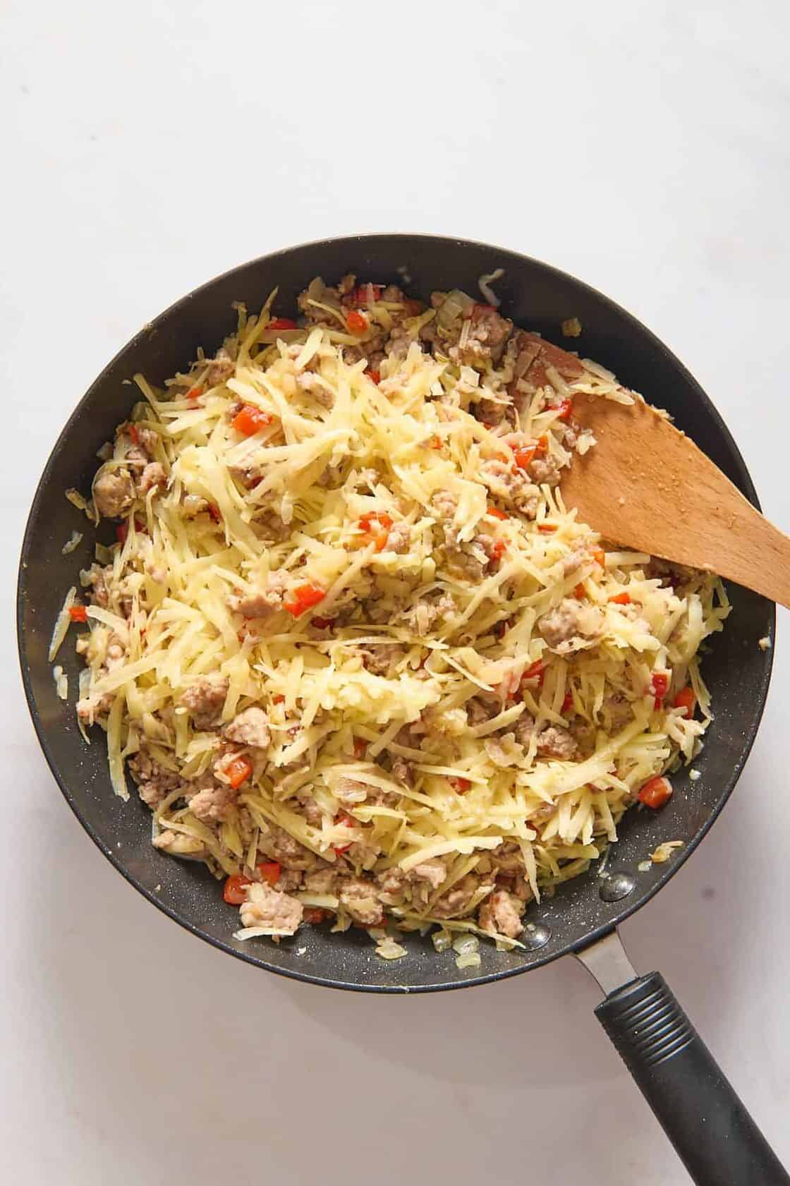 Filling for breakfast casserole with cheese in skillet.