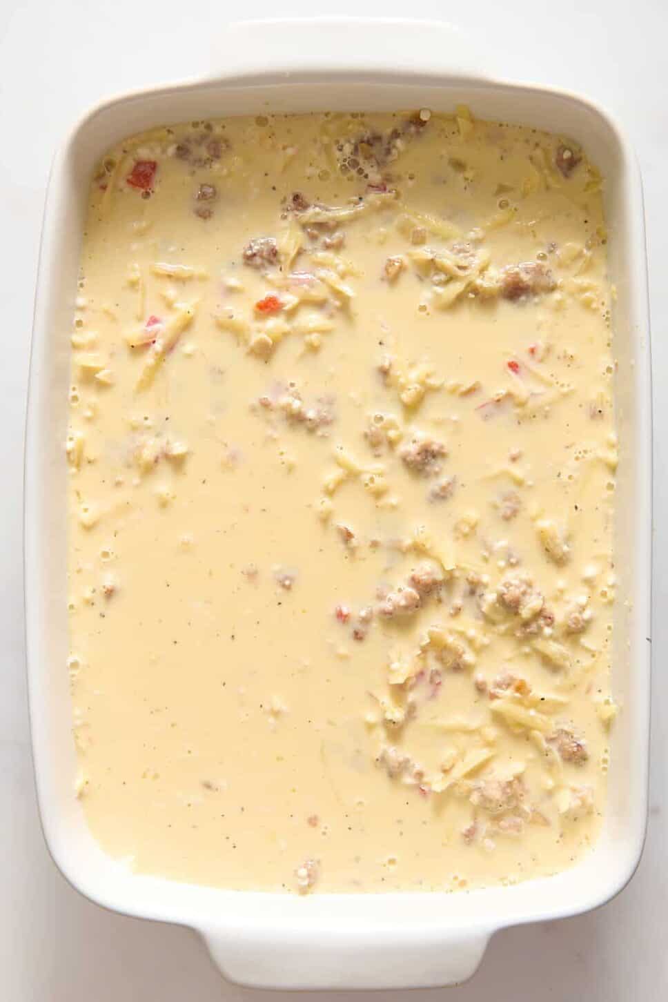 Bisquick breakfast casserole in white casserole dish with pancake batter.