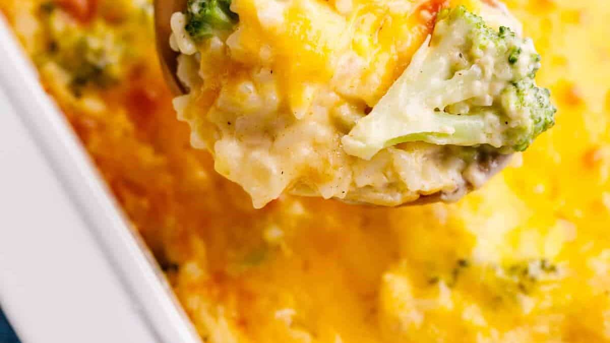 A spoon lifting a bite of broccoli & rice casserole. 