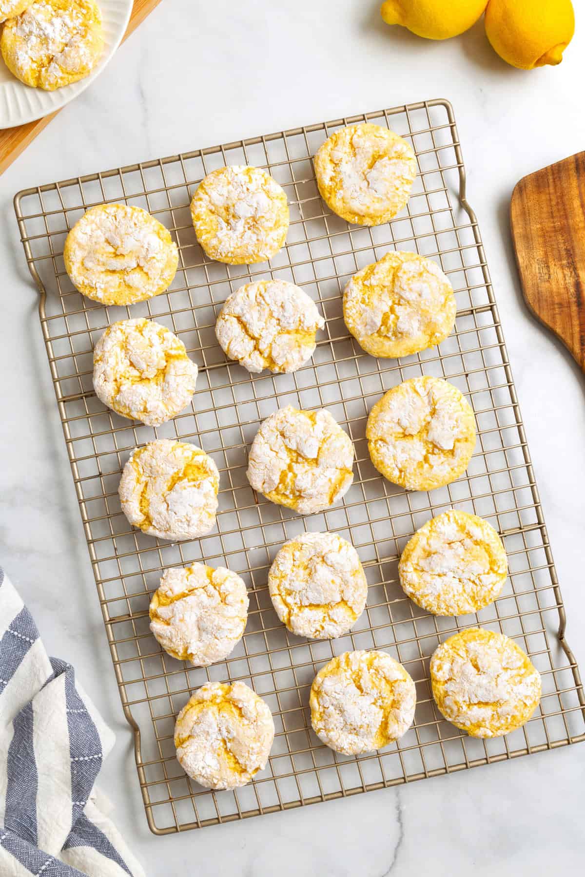 Top down image of 15 cool whip cake mix cookies sitting on a wire cooling rack on top of a kitchen counter.