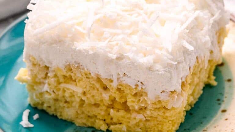 close up view of a slice of coconut poke cake.