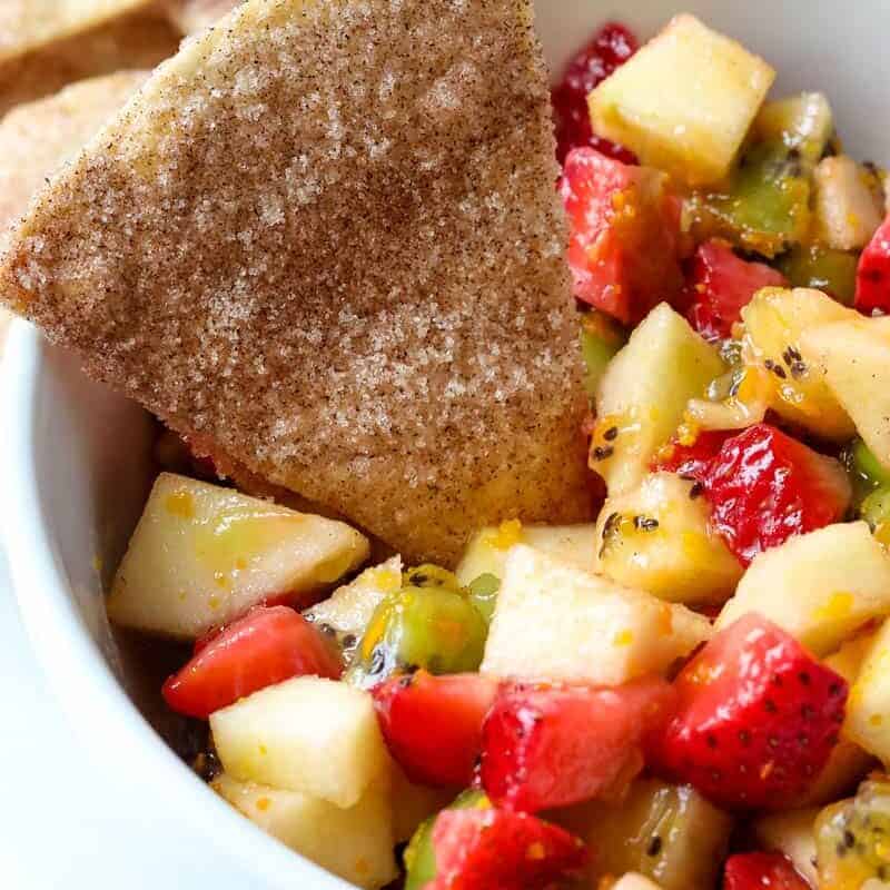 A bowl of fruit salsa with cinnamon chips. 