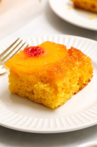 slice of pineapple upside down cake on a white plate.