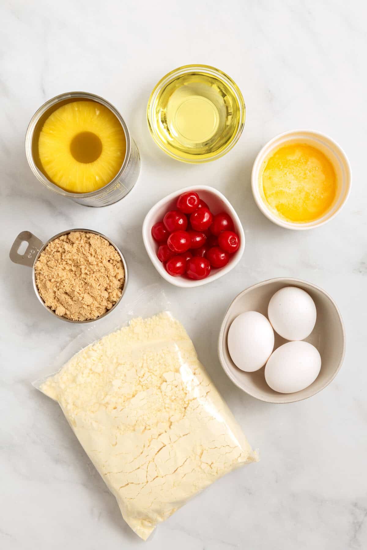 Ingredients for pineapple upside down cake on a white counter. 
