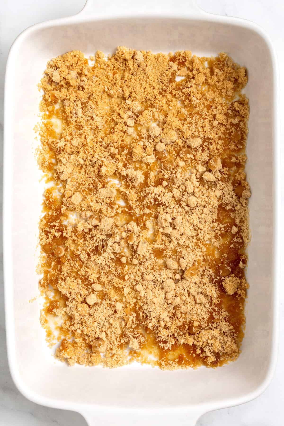 top down image of a casserole dish with brown sugar and melted butter layered at the bottom. 