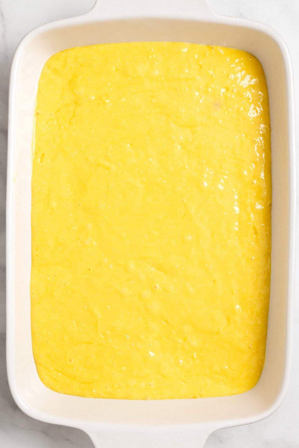 pineapple upside down cake unbaked in white baking dish. 