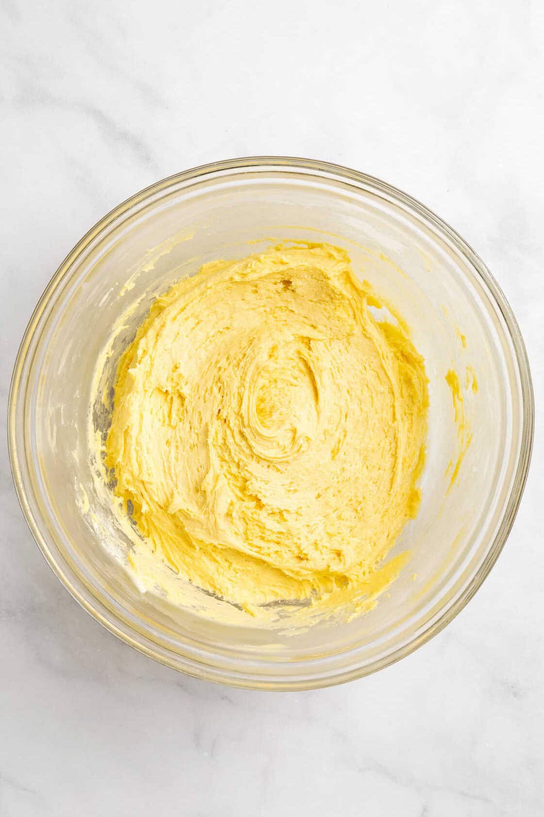 Top down image of cake mix cookie batter in a large glass mixing bowl.