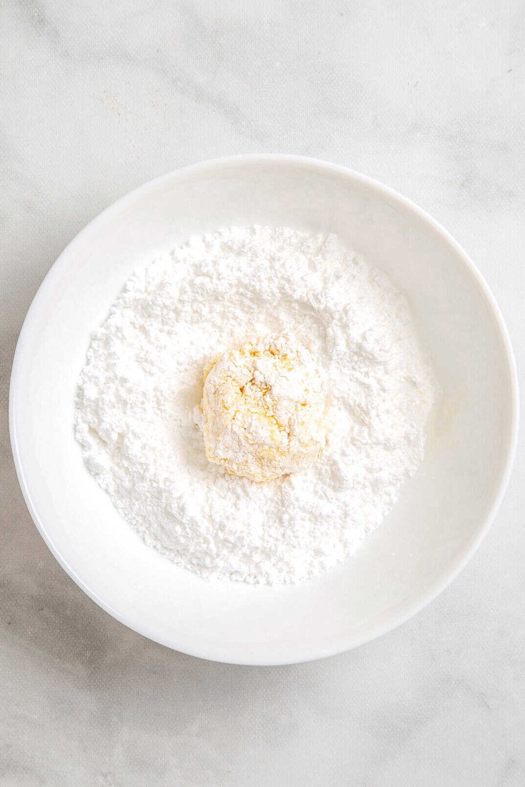 top down image of Cool Whip cake mix cookie dough coated in powdered sugar in a large white bowl.
