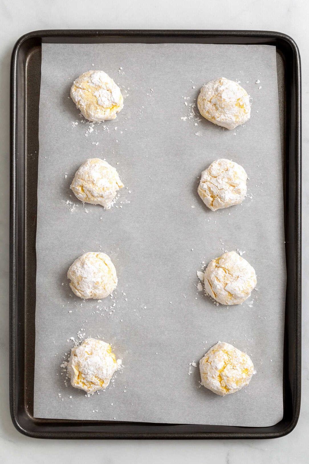 top down Image of Cool Whip cake mix, cookie dough balls sitting on a parchment lined baking tray.